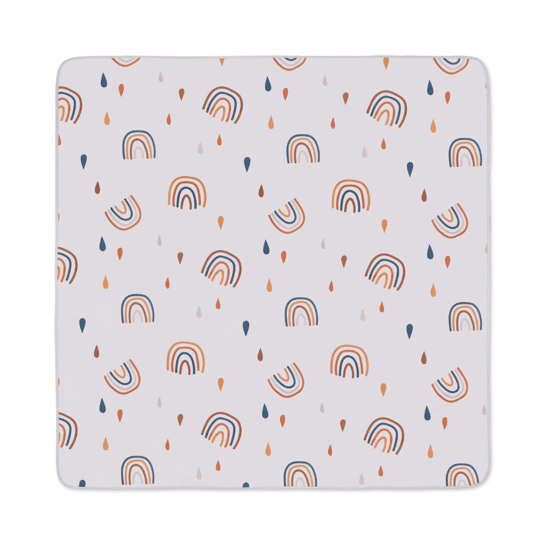 Square baby blanket with rainbow and raindrop pattern on Water Resistant Splat Mat floor cover